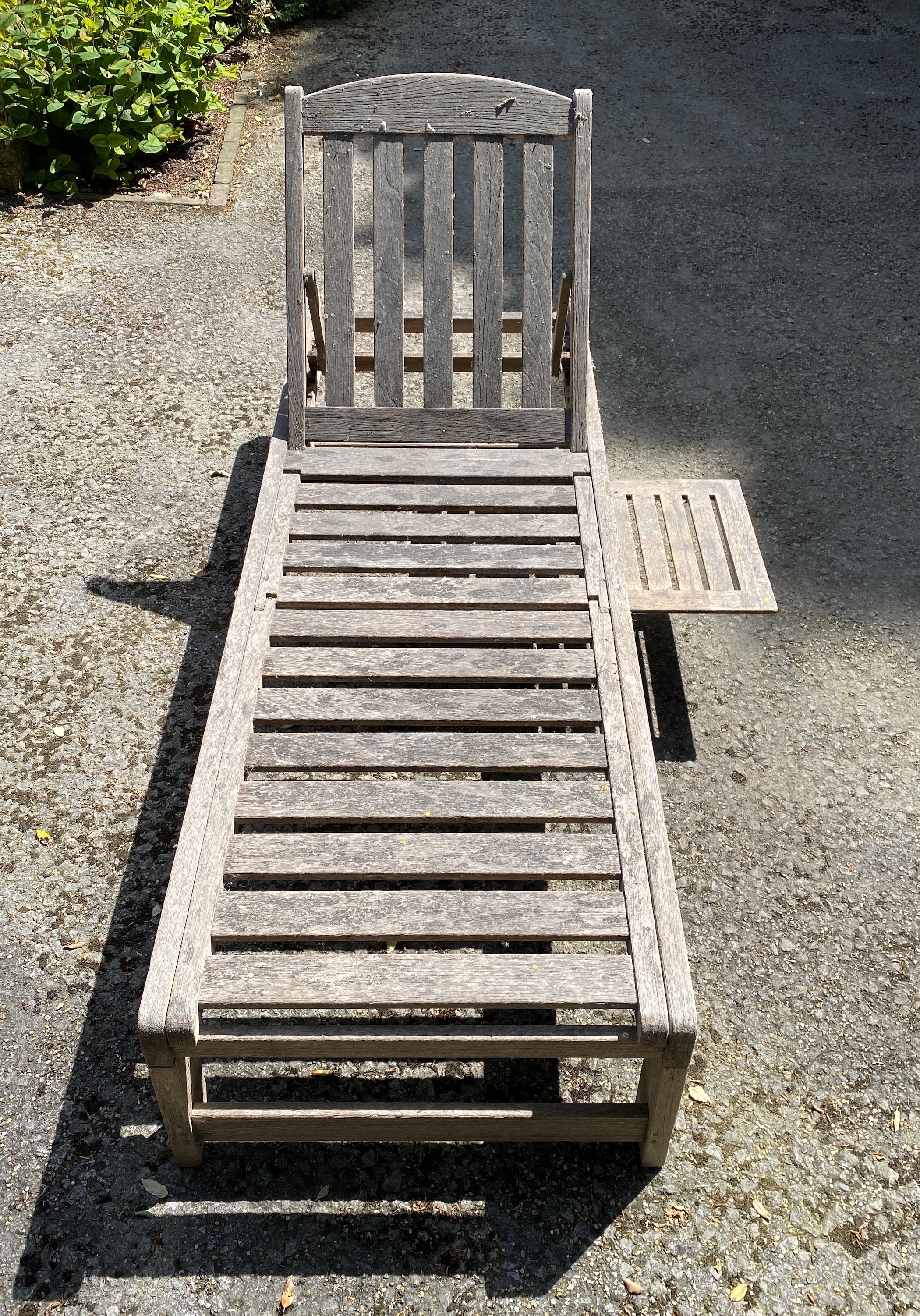 Four slatted teak sun beds, with adjustable backs and integral sliding tables, on two wheels